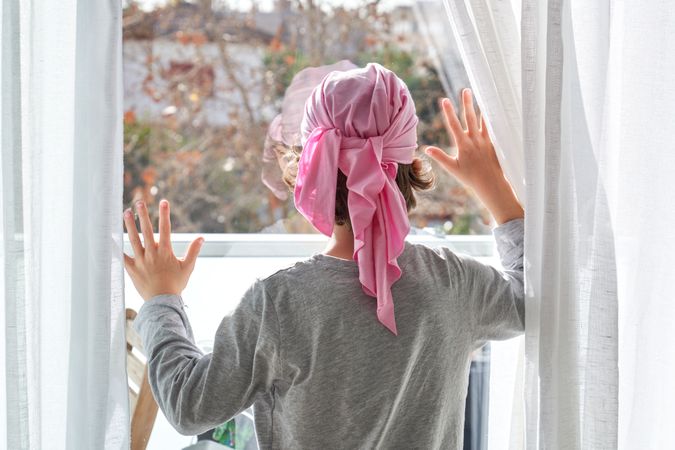 Anonymous kid in pink headband against glass door