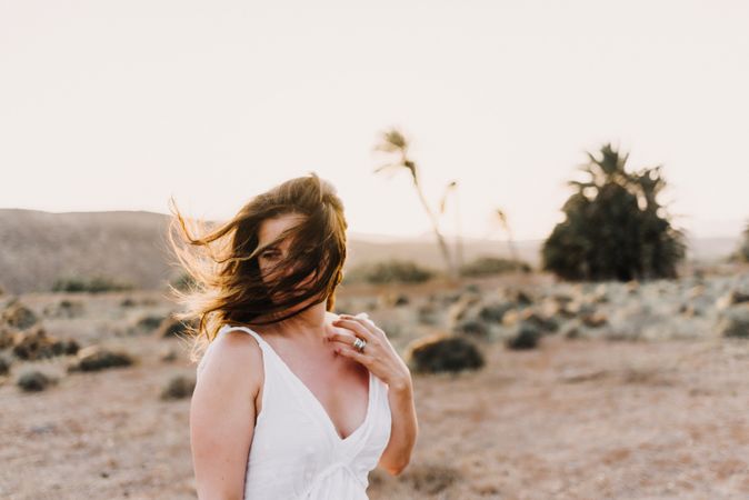 Woman in white dress in dry field in sunlight