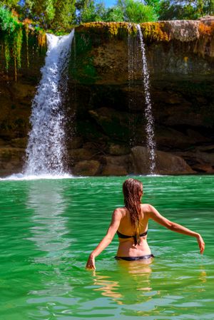 Anonymous female standing near amazing waterfall