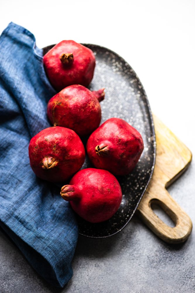 Top view of plate of whole pomegranate on breadboard