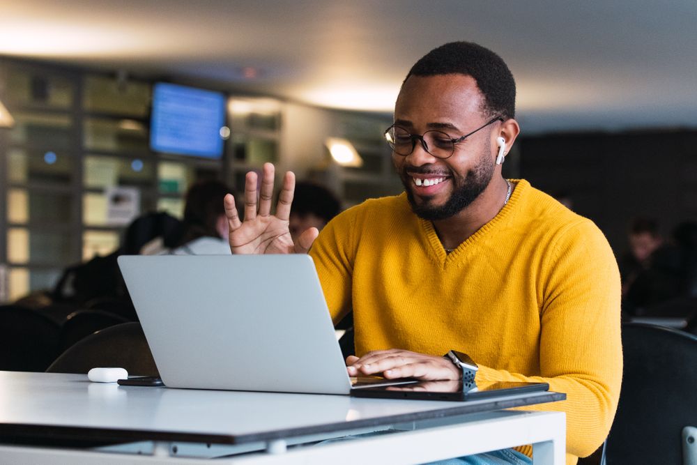 Smiling Black man calling on laptop in workspace