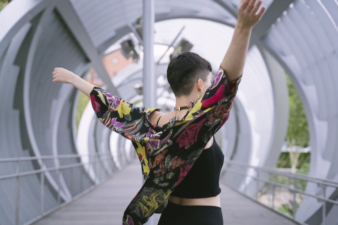 Woman in colorful shirt stretching arms high