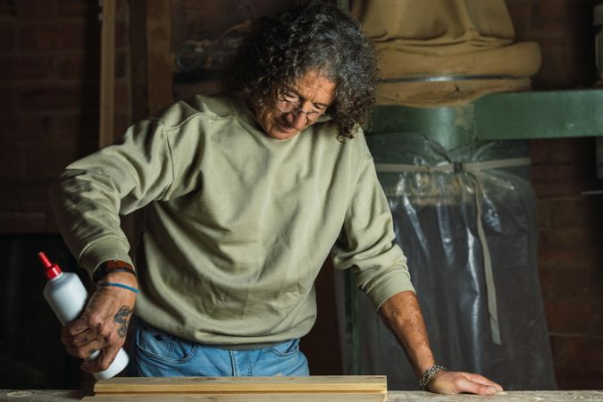 Carpenter gluing wooden board in workshop