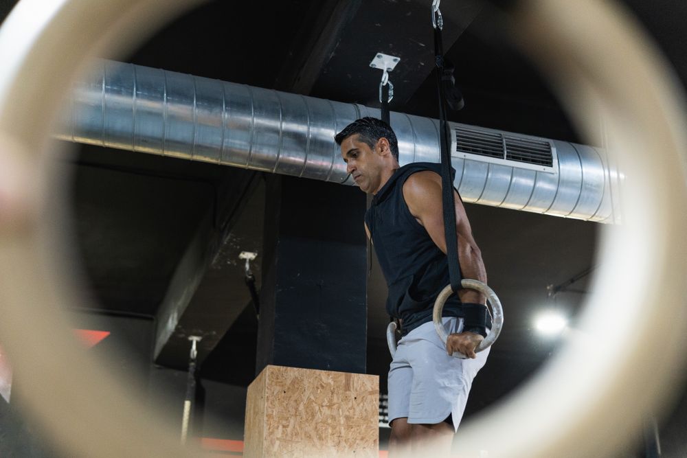 Hispanic sportsman exercising with gymnastic rings