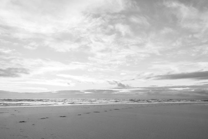Footprints on an empty beach  with waves coming in on overcast day