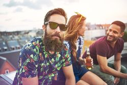 Portrait of man in sunglasses and bold print shit on rooftop with friends