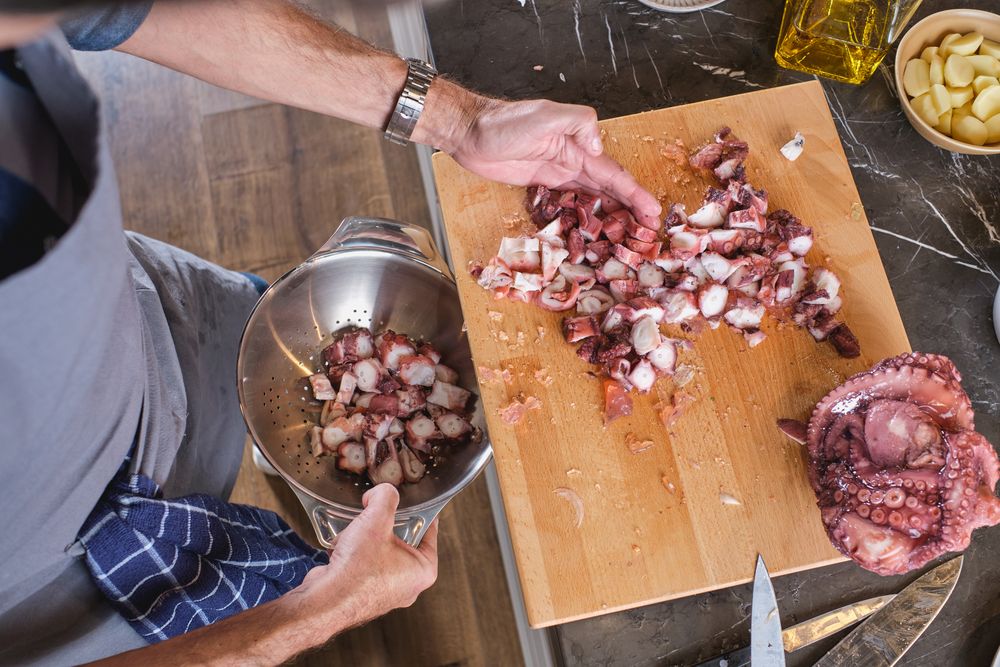 Unrecognizable man putting pieces of octopus in plate