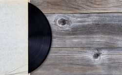 Vintage vinyl music record in paper holder on weathered Wood