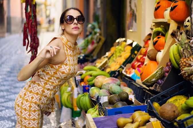 Glamorous woman leaning over fresh fruit in outdoor market