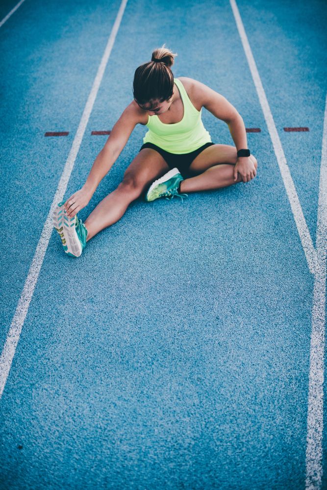 Young woman stretching in a land on a track field