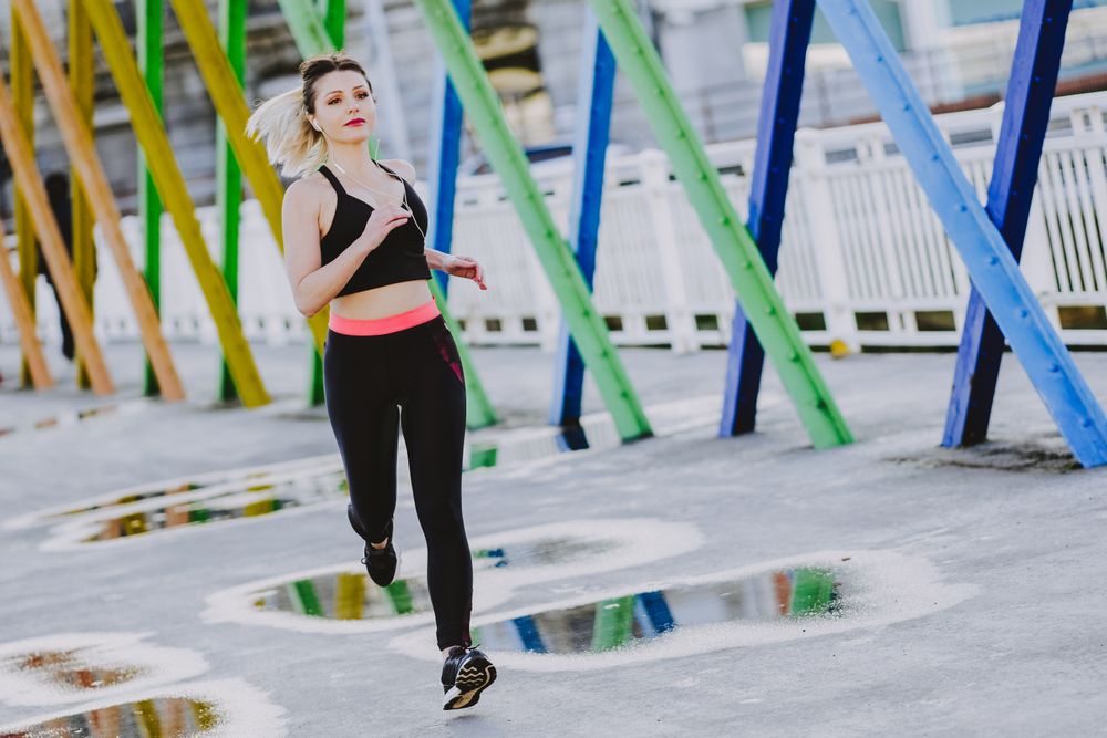 Woman with earphones running on street