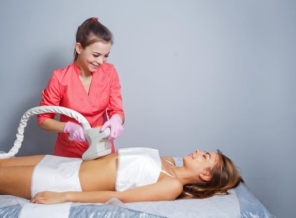 Cosmetologist doing beauty treatment on client’s midsection