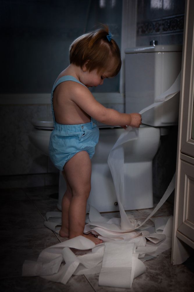 Toddler pulling toilet paper in the bathroom