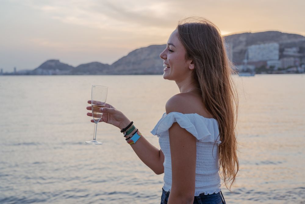 Young woman enjoying wine near sea