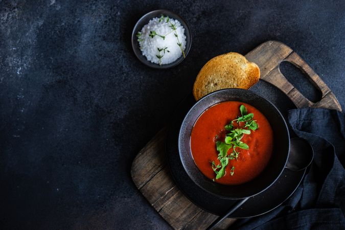 Top view of gazpacho soup served in dark bowl with toast with copy space