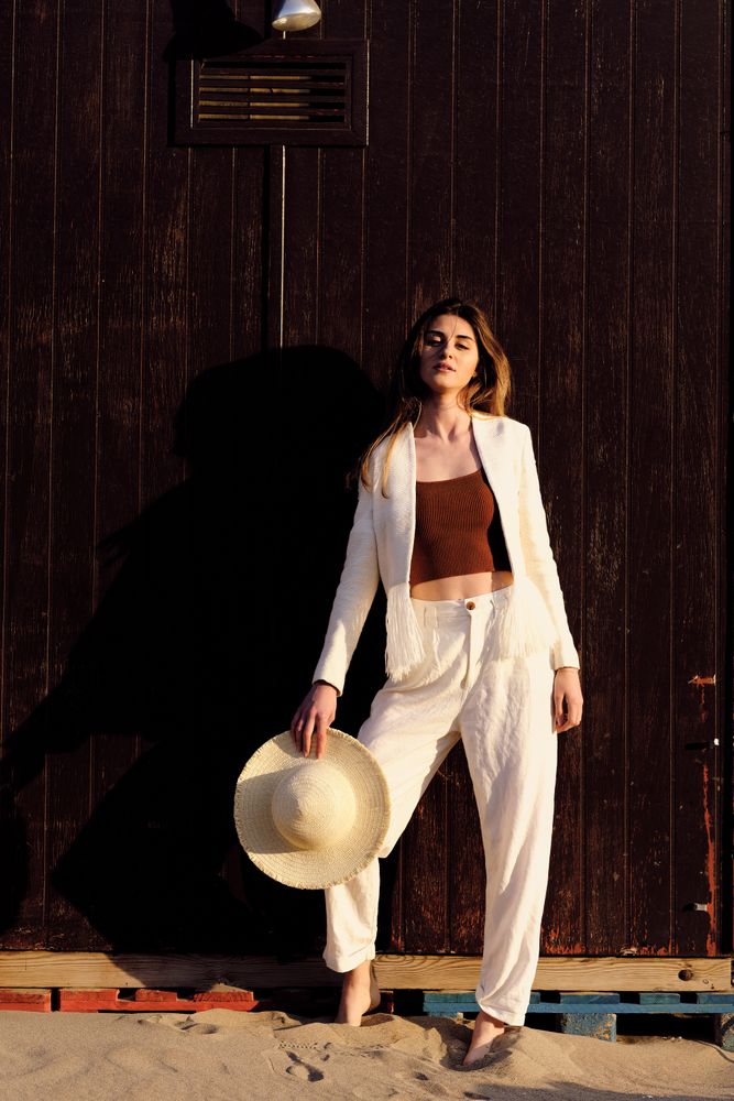 A long hair fashion model with a hat at the beach with a dark background