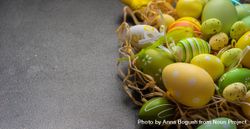 Easter decorations scattered in straw on grey table bDjaAy