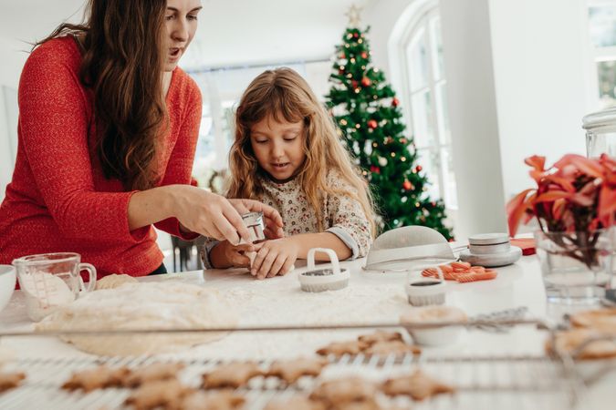 Mother and daughter preparing Christmas cookies with cutter