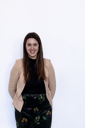 Happy female leaning on wall smiling at camera