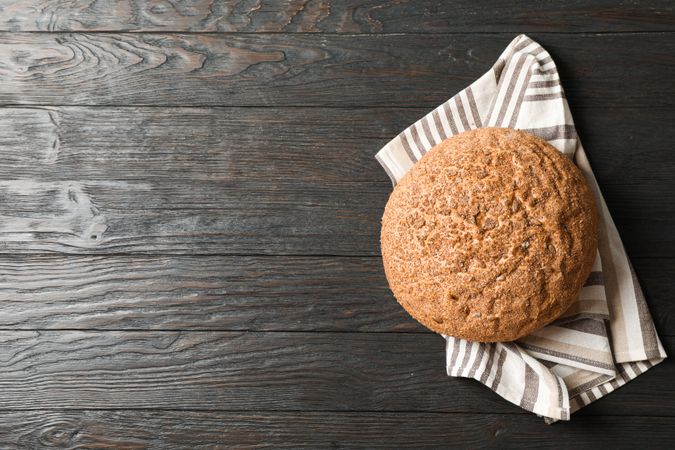 Bread on kitchen towel on wooden background, space for text and top view