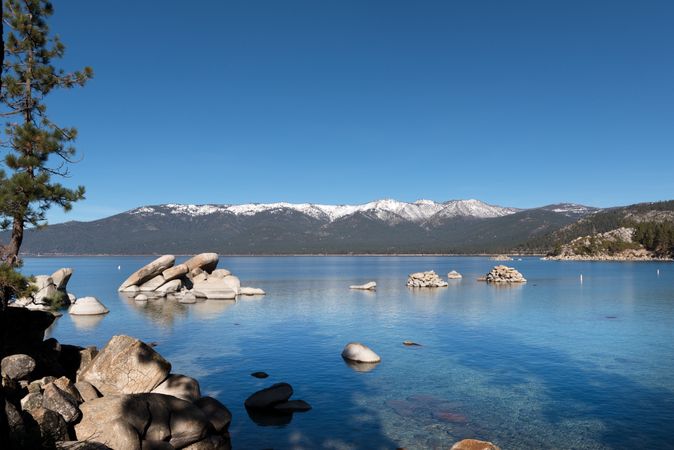 Lake Tahoe with rocks and snowy mountains in background