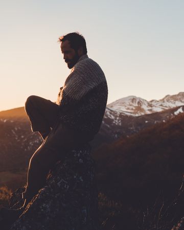 Female traveler sitting on mountain slope at sunset