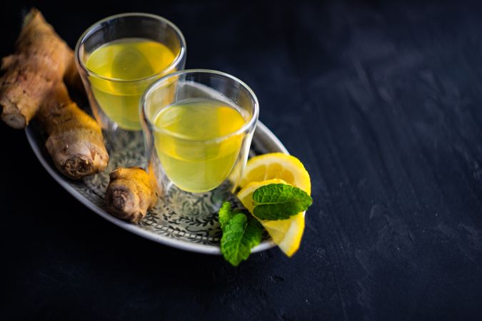 Two yellow detox drinks with ginger and lemon with copy space