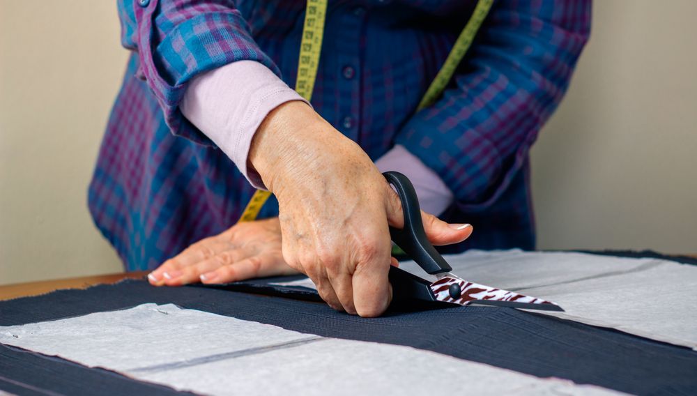 Hands of dressmaker cutting a cloth