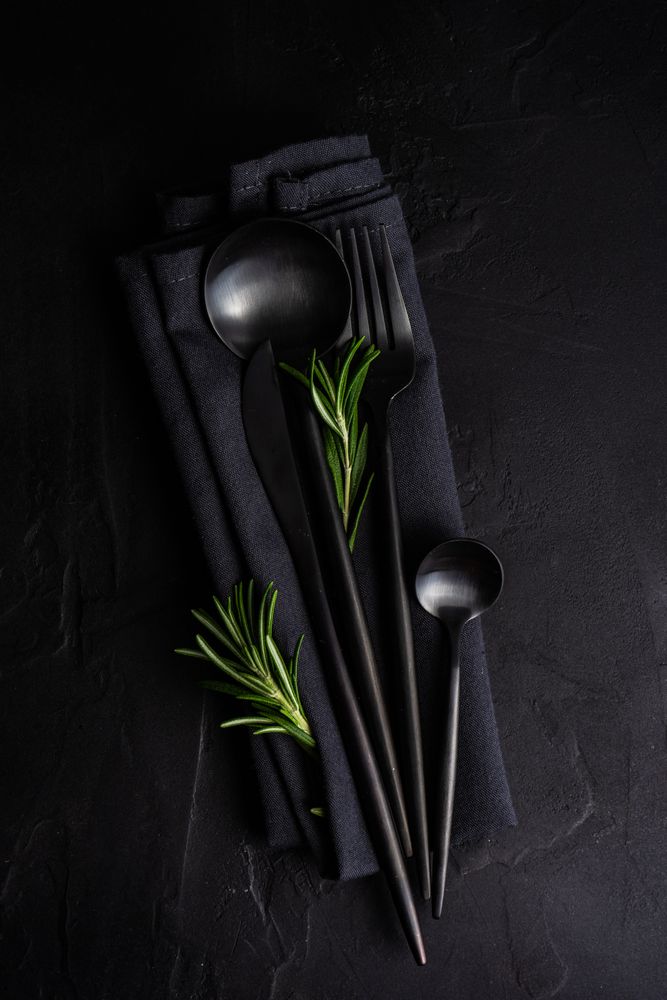 Sleek dark table napkin with cutlery with rosemary sprig