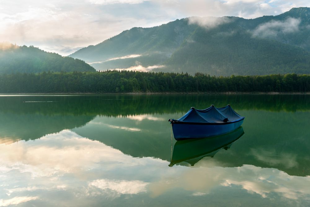 Boat on Lake Sylvenstein and the mountain reflection in the water