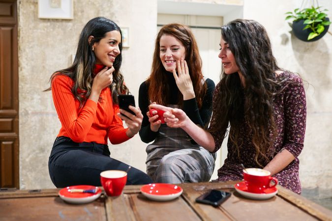 Friend sharing phone screen to her friends in coffee shop