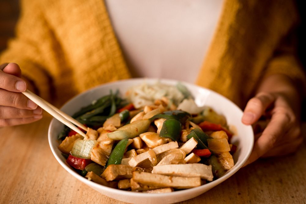 Female eating bowl of cooked appetizing diet dish