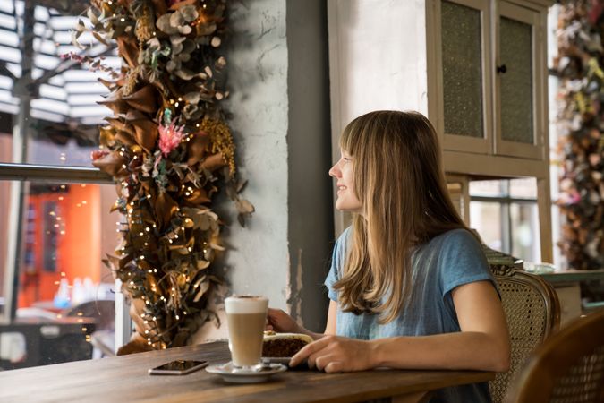 Cheerful woman using a phone in cafe