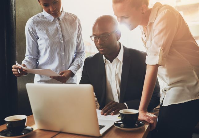 Multi-ethnic group gathered around a laptop