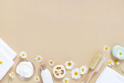 Relaxing bath salts, loofah and brushes on beige background with copy space