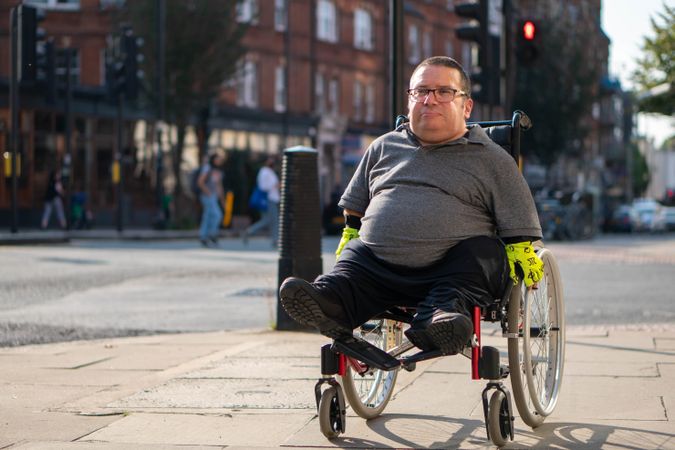 Man in wheelchair going through city sidewalk