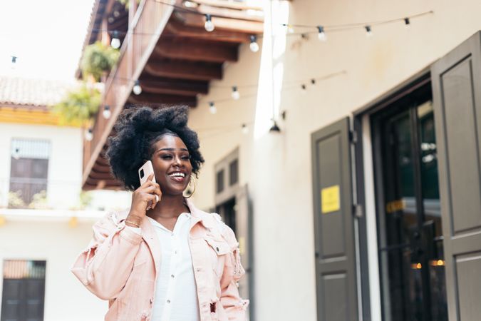 Stylish Black woman walking on the city street talking on the phone
