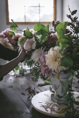Composition of flowers and plants in vintage vase on board