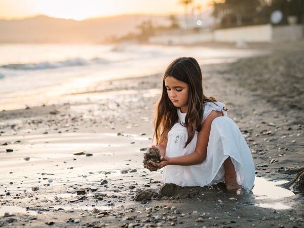 Adorable girl playing with sand on beach