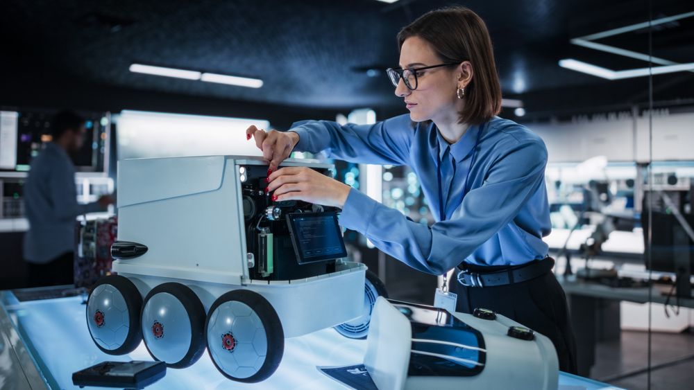 Portrait of a Female Technical Specialist Working in High Tech Research Laboratory with Modern Equipment: Female Adjusting Equipment on a Delivery Robot