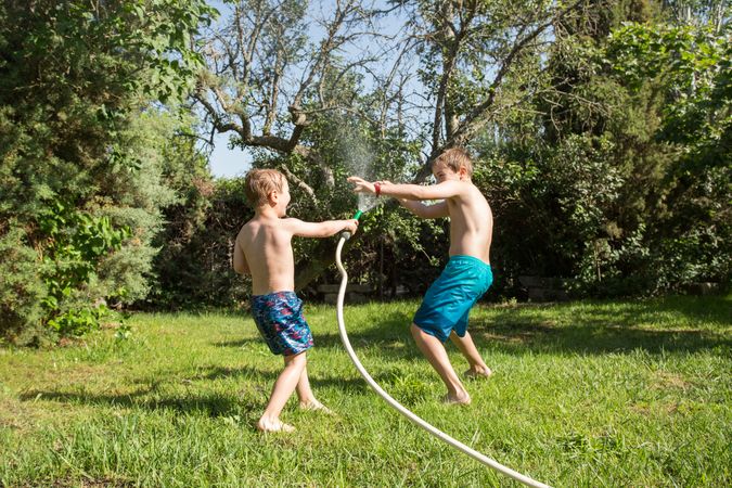 Little kids in swimwear having fun with splashing water