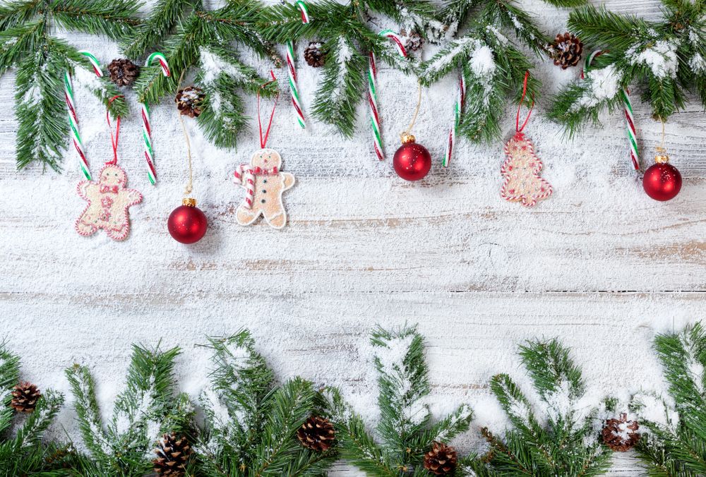Snowy Christmas branches with associated ornaments on rustic wooden background