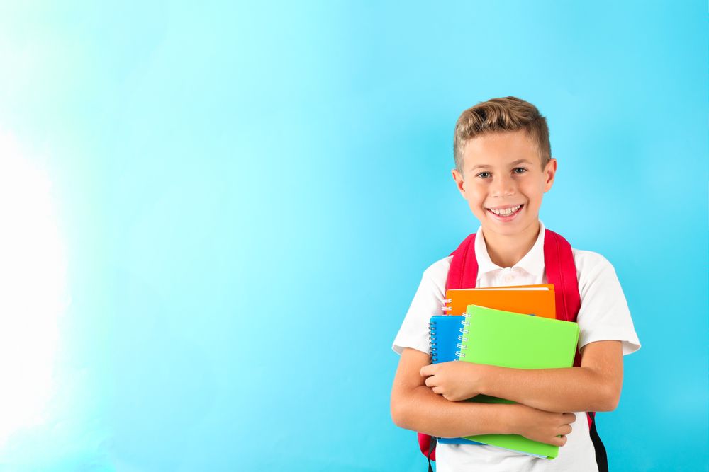 Boy with copybooks and backpack against color background, space for text