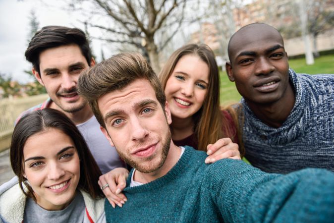 Group of friends looking down at camera and posing for selfie