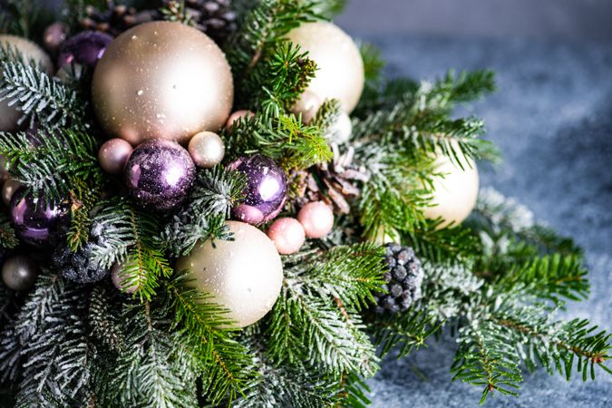 Close up of purple and gold Christmas baubles in pine centerpiece