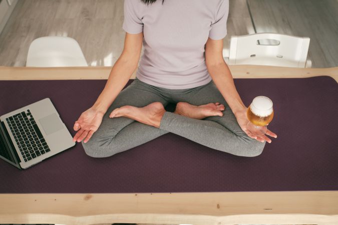 Unrecognizable female meditating with beer near laptop
