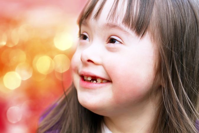 Closeup portrait of smiling young girl with Down syndrome outside