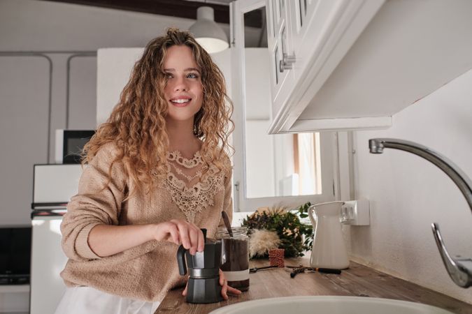 Young housewife preparing coffee in kitchen