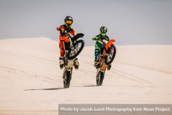 Skillful stunt bikers riding motorcycle on one wheel in desert 5nnoA5