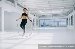 Woman exercising and jumping rope inside fitness studio bezQp0